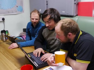 (photo: Rob Lambert watches on as Richmond and Spencer prepare their answers in the Living Caboose)